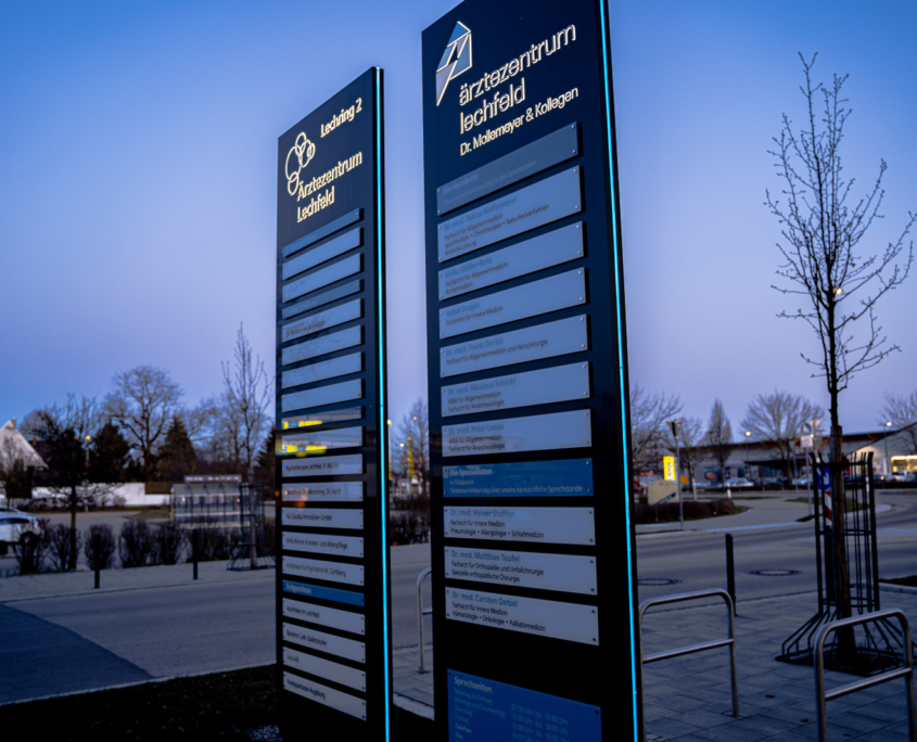 Slimline Pylon mit seitlicher Leuchtkontur, Glasschildern und durchgesteckten LED-Buchstaben und Logo